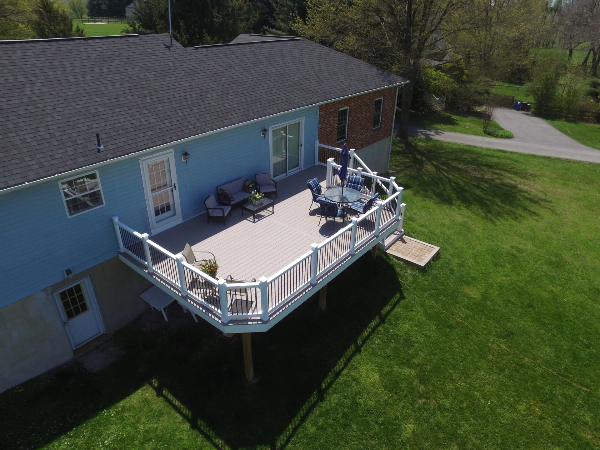 Aerial view of elevated residential deck with rail and outdoor living furniture