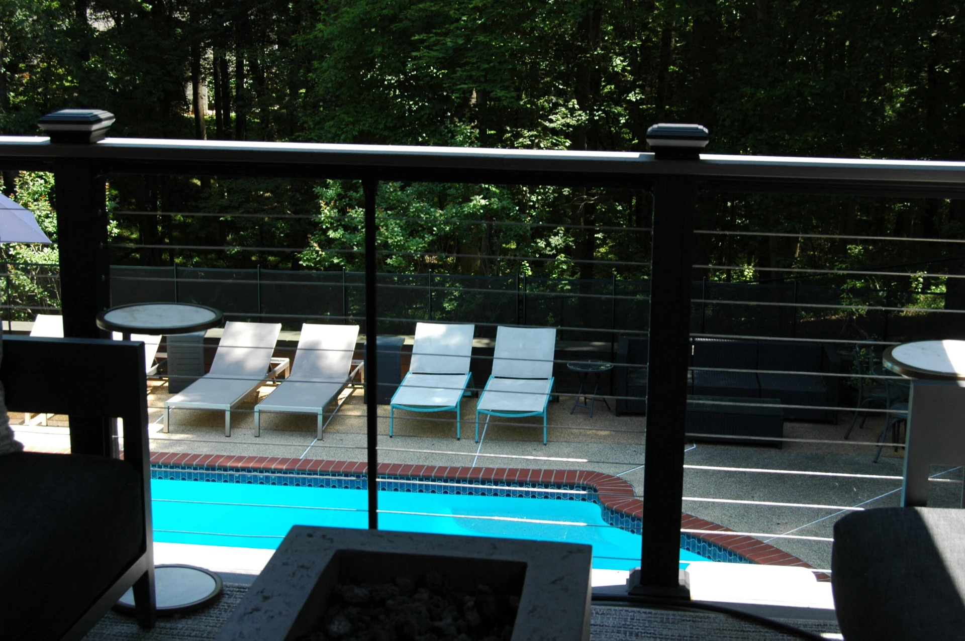 Aluminum railing with fire pit and a pool below with nature scenery