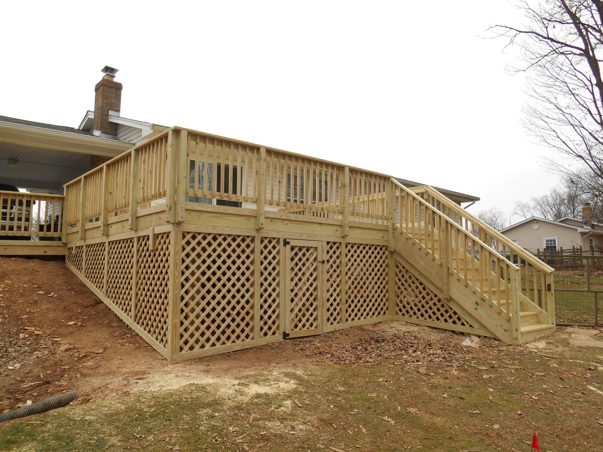 Bamboo stairs and deck with railing featuring bamboo skirting with a door