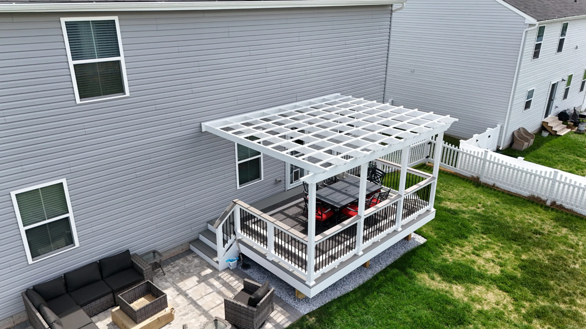 Elevated deck with white pergola and outdoor furniture with white fence