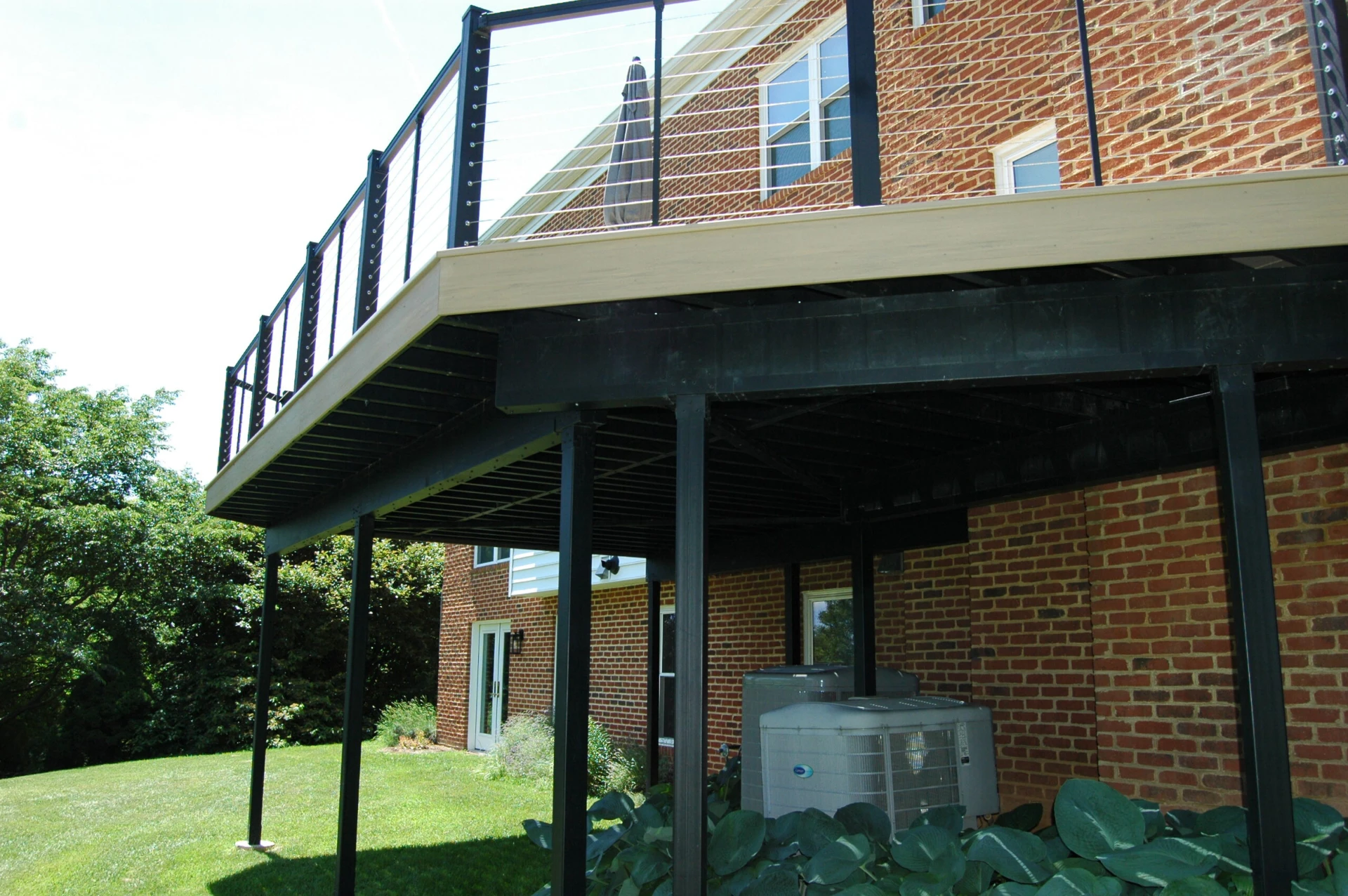 Elevated deck with wire railing and plants below of the deck
