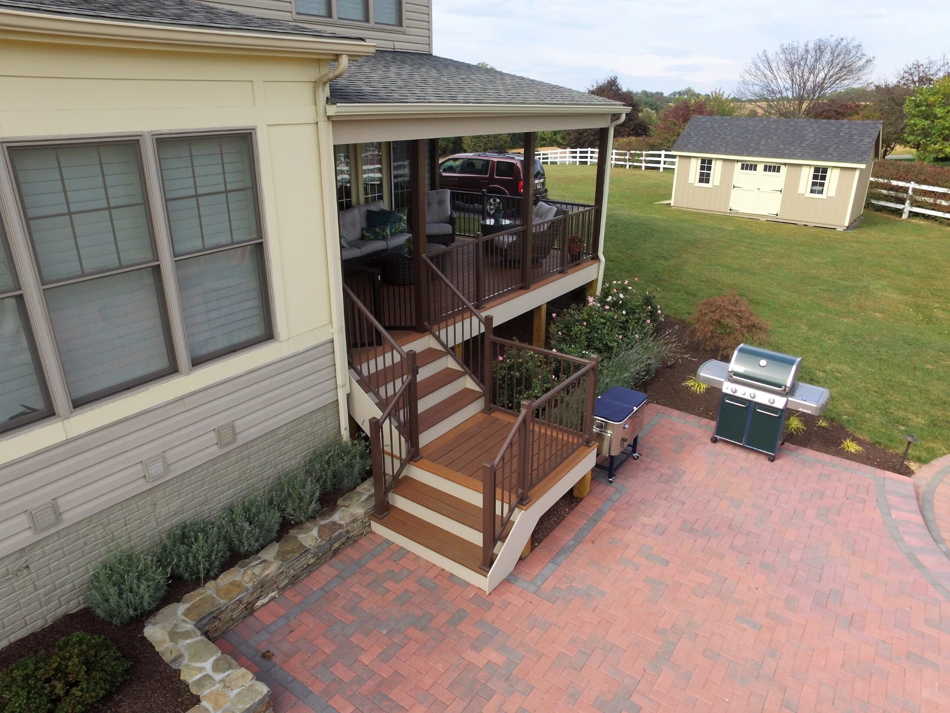 Elevated hard commercial wood deck with wooden railing and furniture inside the porch