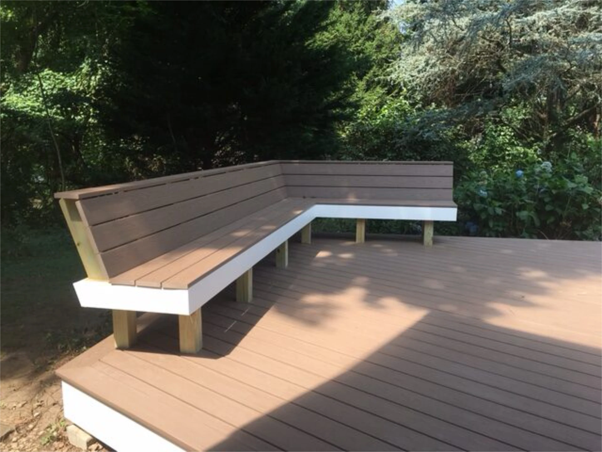 Hard wood deck with wood couch and trees on the backside