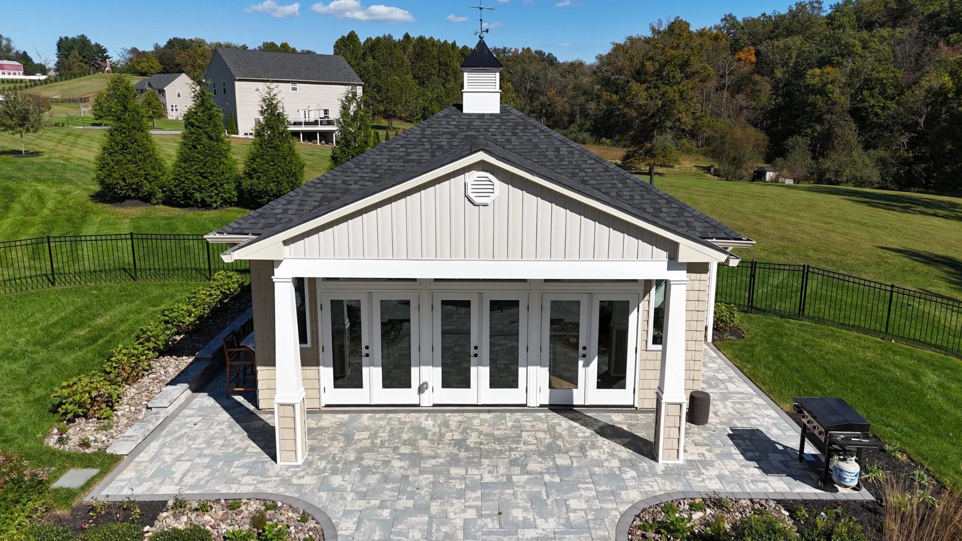 Paver patio with three white door and black railing on the backside of the house