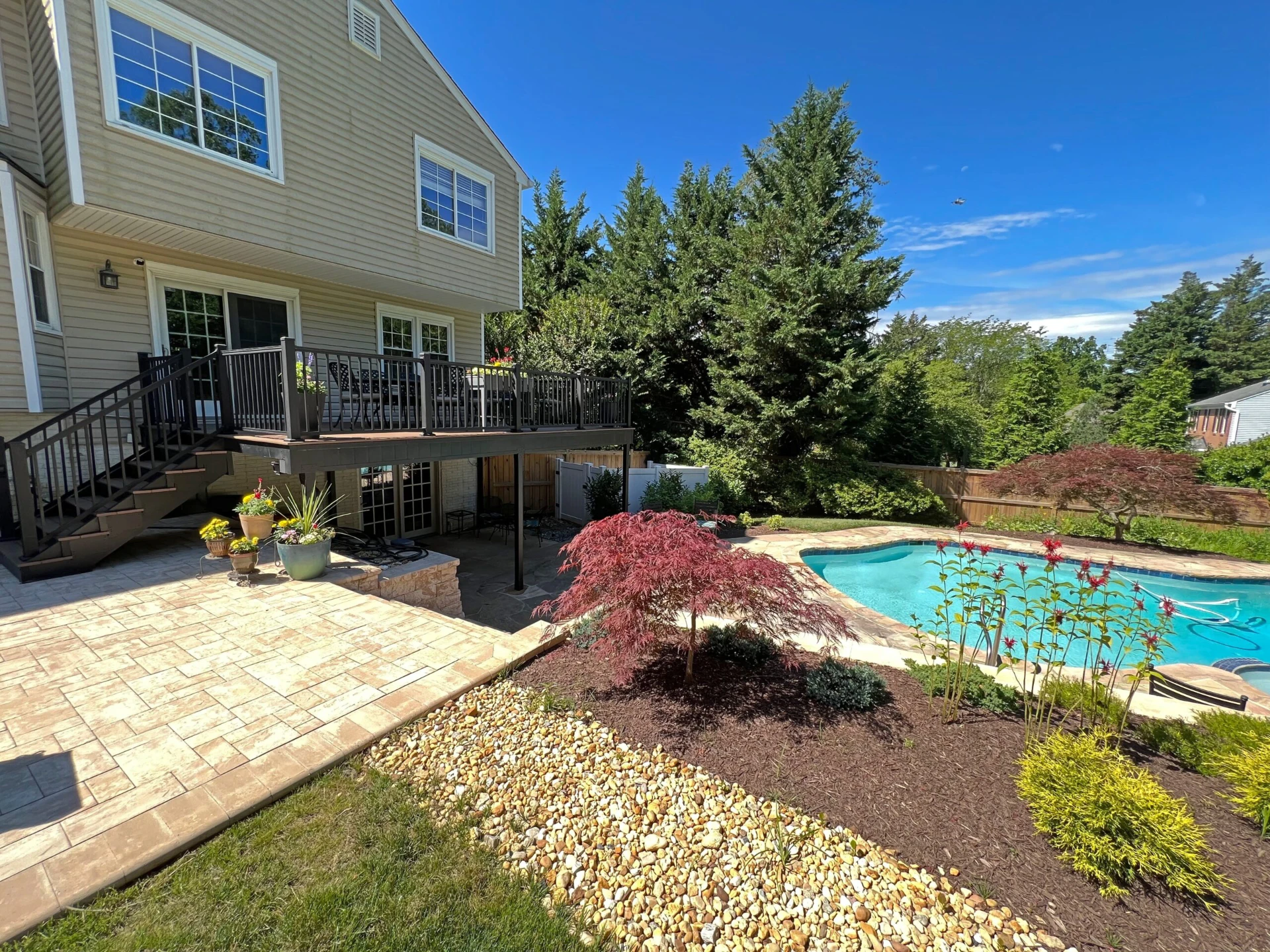 Perspective view of the elevated deck with black railing with pool on the bottom side and overlooking view
