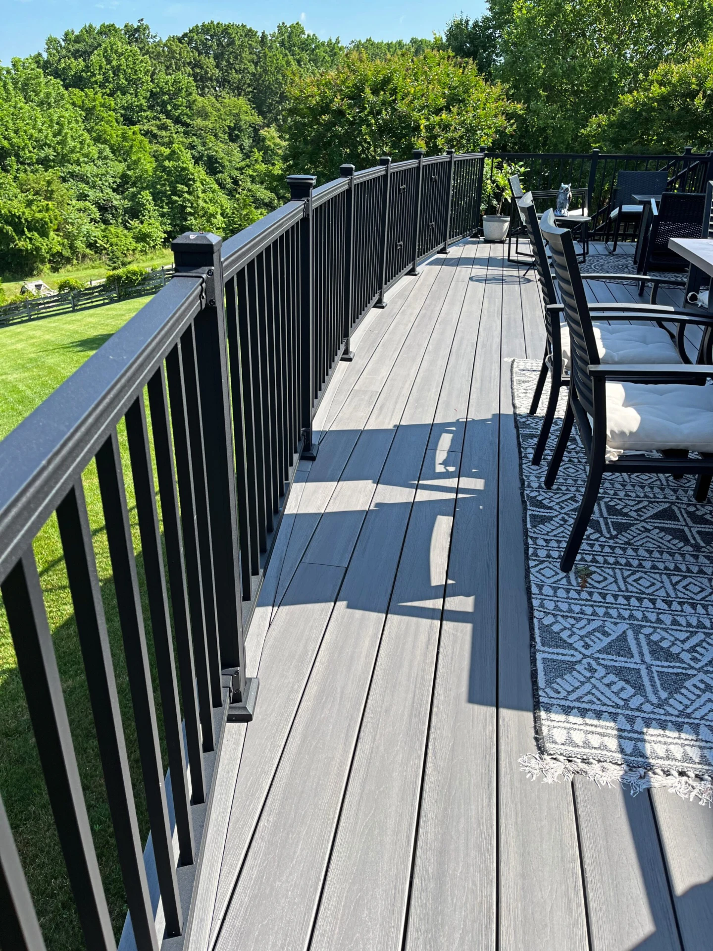 Residential sun kissed deck with long black deck railing and furniture
