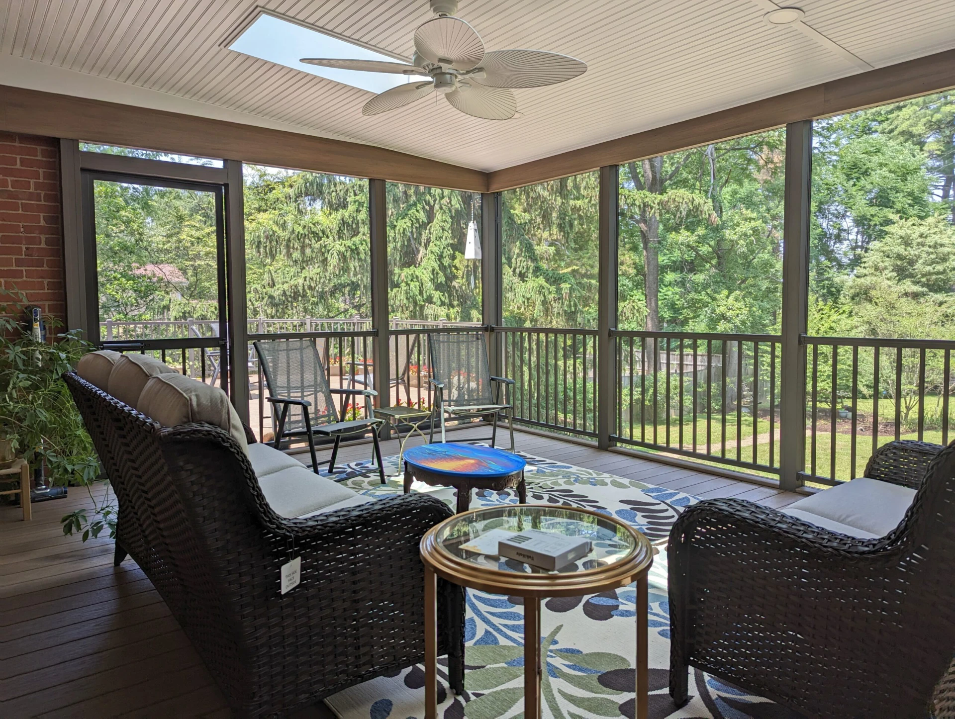 Screen porch with fan and bronze railing with overlooking nature view