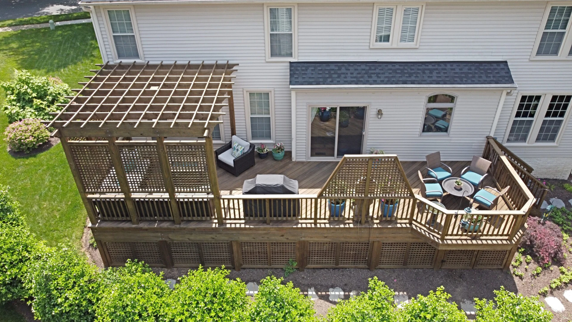 Wooden residential deck with skirting and wooden pergola with outdoor living furniture